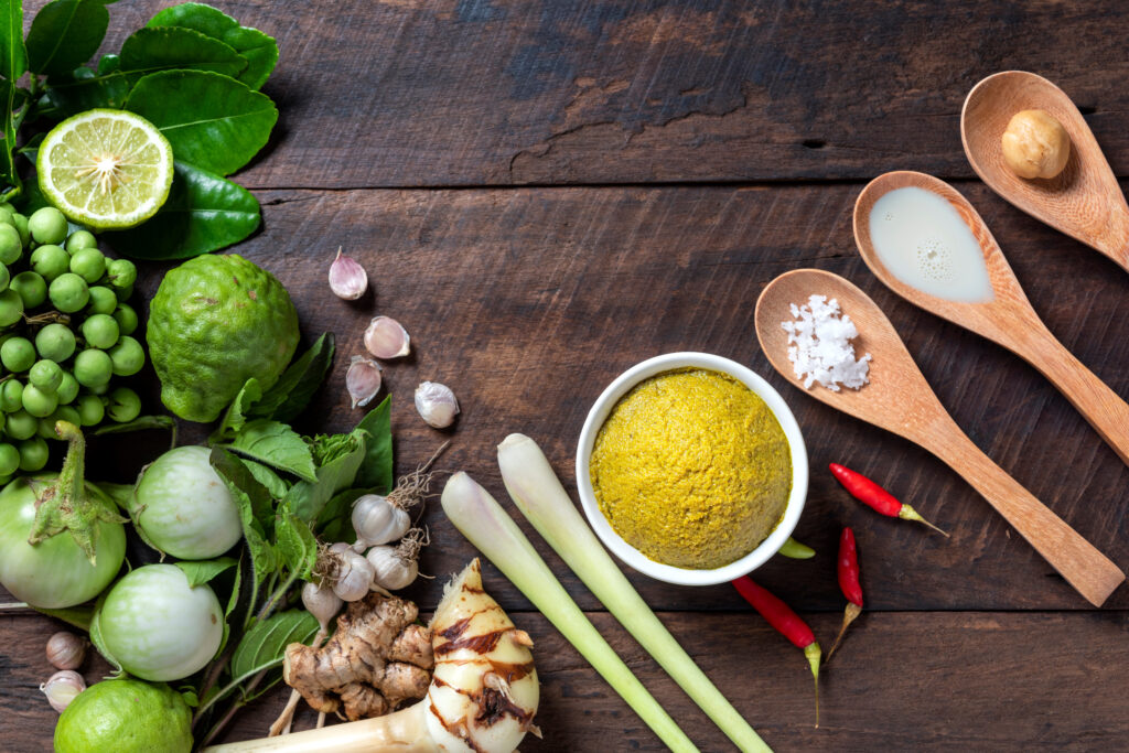 Traditional Thai green curry ingredients with herbs, spices, and coconut milk representing the sweet and spicy balance of Thai flavor